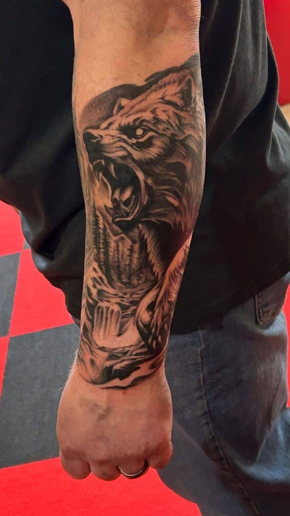 A detailed black and grey realism tattoo of a roaring animal on a forearm, custom designed at Mayhem Ink Tattoo in Nashua, NH.