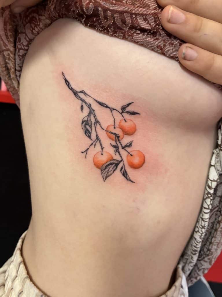 Small orange rose floral tattoo on ribcage done by a tattoo artist at Mayhem Ink Tattoo in Nashua, NH.