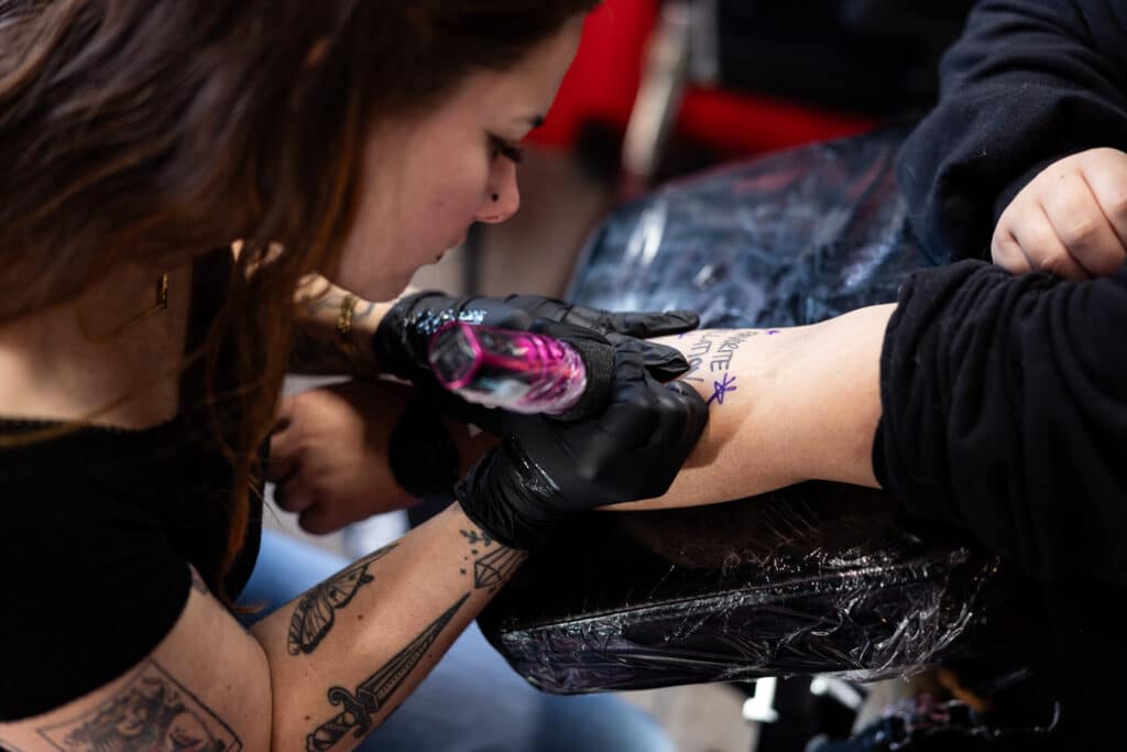 Tattoo artist Bri working on client arm at Mayhem Ink Tattoo in Nashua, NH